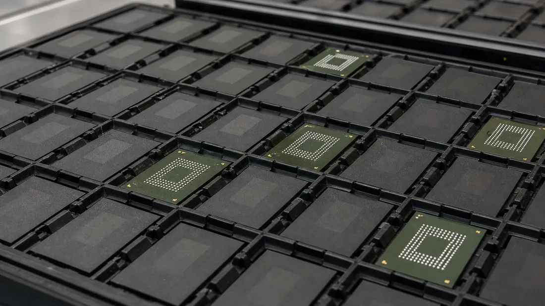 Engineer comparing two trays of embedded eMMC and UFS components at an electronics qualification bench