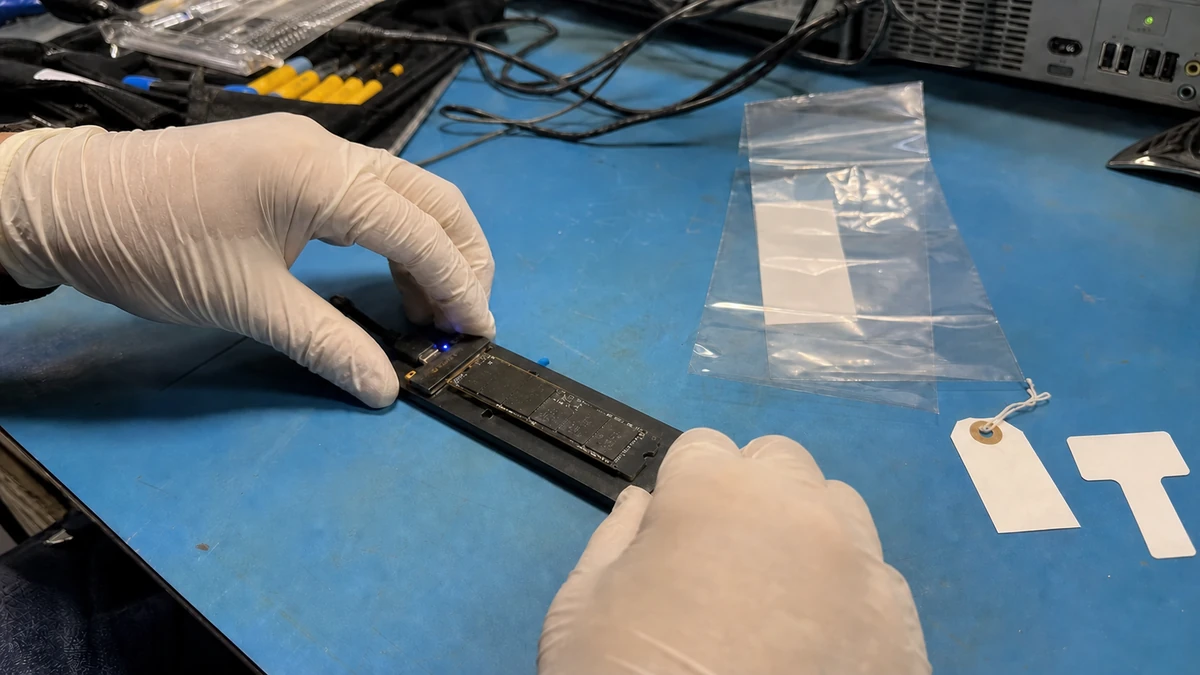 Technician documenting an NVMe SSD on a used ESD bench before failure analysis