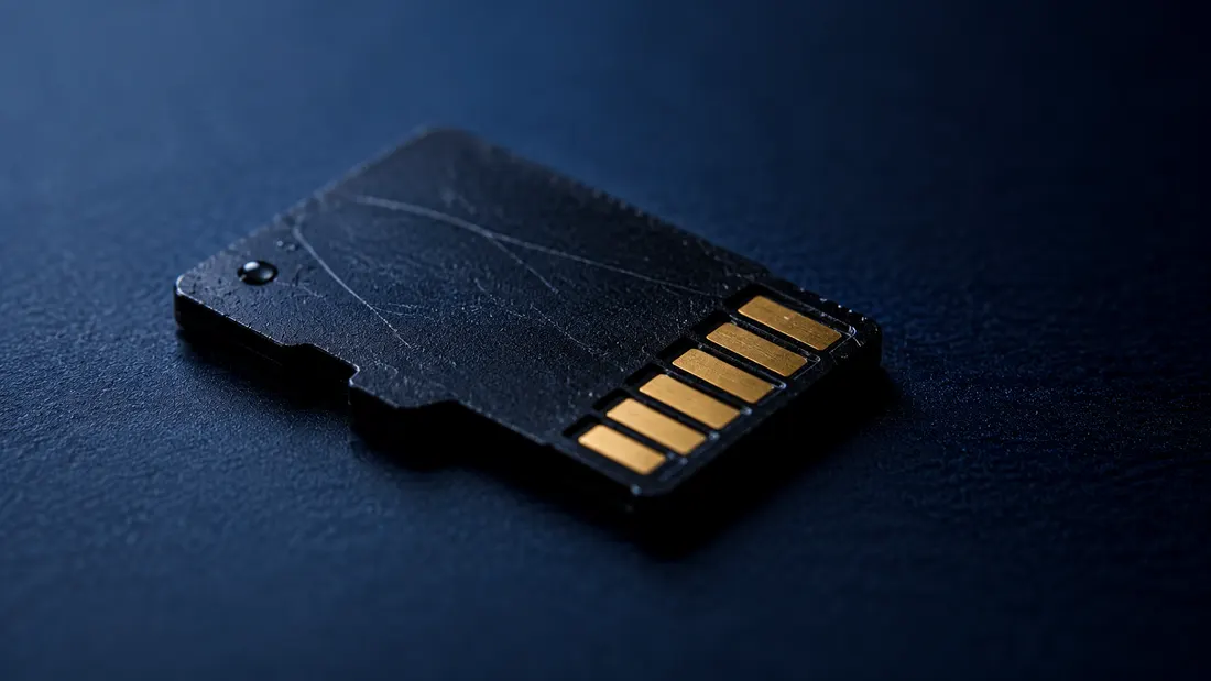 Close-up of a black microSD memory card on a dark surface — failure modes and data recovery